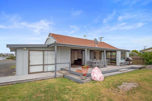 a small house with a porch and a patio at The Sunrise Bach - One Tree Point Holiday Home in One Tree Point