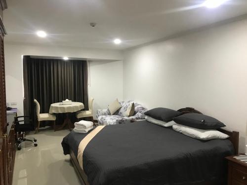 a bedroom with a large bed and a table at Omni Tower Cozy Apartment Near NANA BTS in Bangkok