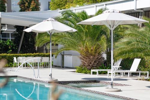 two white umbrellas and chairs next to a pool at Boulevard North Lakes in North Lakes