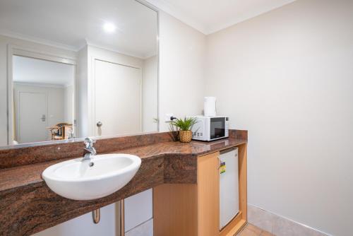 a bathroom with a sink and a microwave at Heritage Inn Bathurst in Bathurst