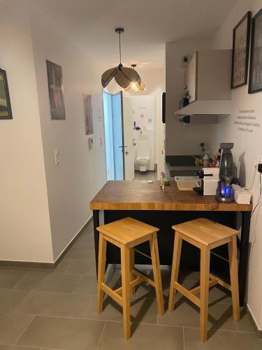 une cuisine avec un comptoir en bois et deux tabourets dans l'établissement joli petit nid douillet en centre ville, à La Rochelle