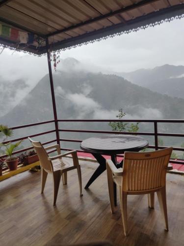a table and chairs on a balcony with a view at Chamba Nest in Chamba