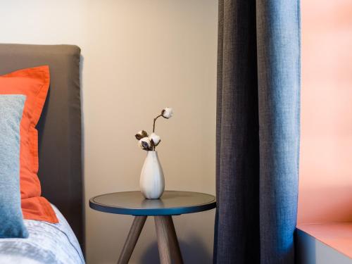 une table avec un vase à côté d'un lit dans l'établissement Hyper centre chambre au calme, à Lille