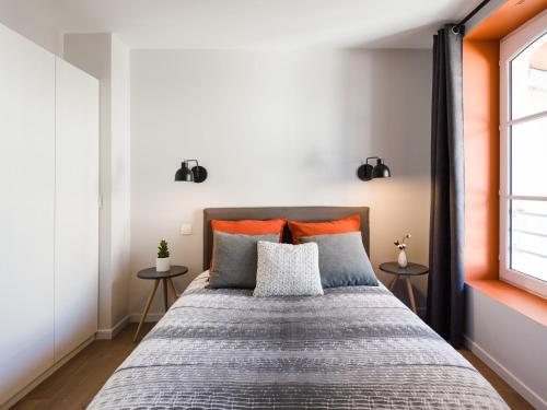 um quarto com uma cama grande com almofadas cor-de-laranja e cinzenta em Hyper centre chambre au calme em Lille