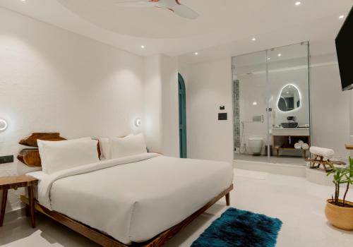 a white bedroom with a large bed and a bathroom at Moustache Udaipur Luxuria in Udaipur