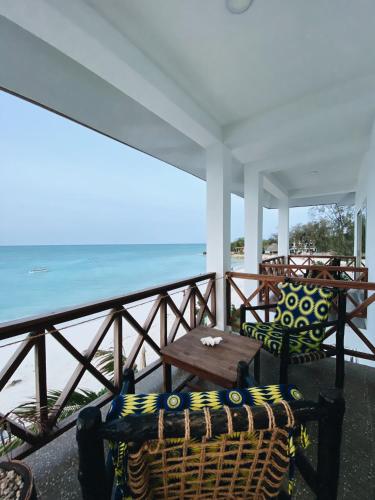 a balcony with chairs and a table and the ocean at Crystal Beach Nungwi in Nungwi