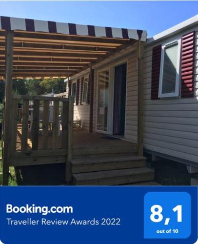 - une véranda couverte d'une maison avec une terrasse en bois dans l'établissement Fun Family Home - Camping Les Charmettes, aux Mathes