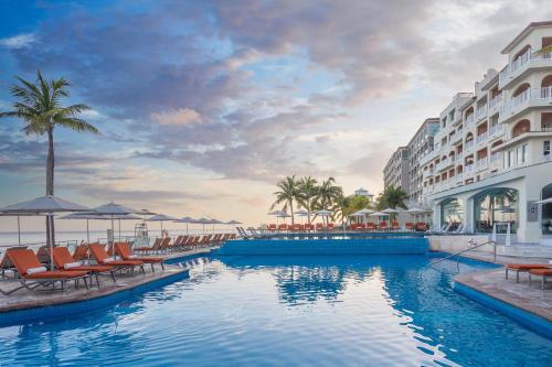 a pool at a resort with chairs and umbrellas at Cozumel Palace-All Inclusive in Cozumel