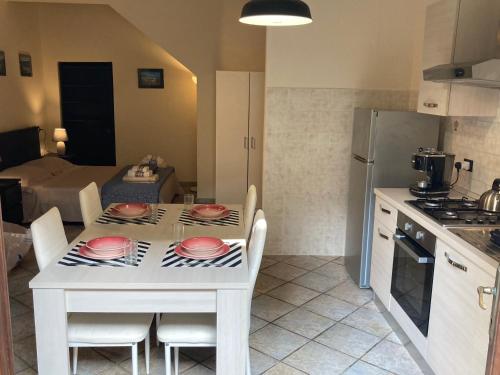 a kitchen with a white table with chairs and a kitchen with a kitchen at Great studio apartment in the heart of Chianni in Chianni