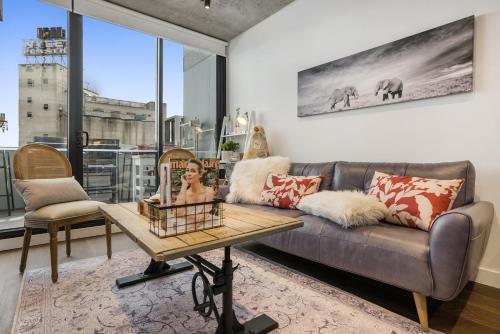 a woman sitting on a couch in a living room at Luxury African themed apartment☆10min to MCG & Swan St☆On-site Parking☆Balcony☆Rooftop deck☆Gym☆ in Melbourne