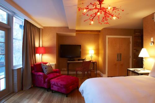 a hotel room with a bed and a chair and a tv at The Ivy at Verity in Toronto