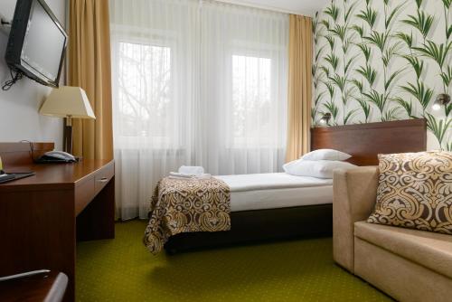 a bedroom with a bed and a chair and a window at Hotel Zielony in Poznań