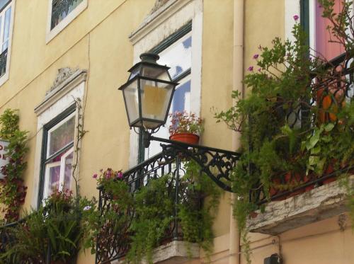 a street light on the side of a building with flowers at Dias e Dominguez in Lisbon