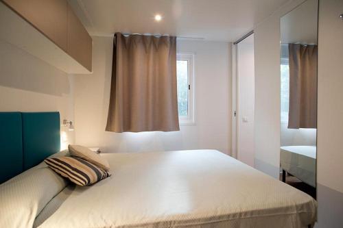 a bedroom with a large white bed with a window at Camping Europa in Capoliveri