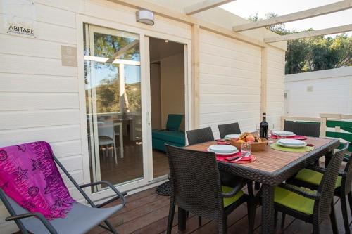 a wooden table and chairs on a patio with a table and a glass door at Camping Europa in Capoliveri