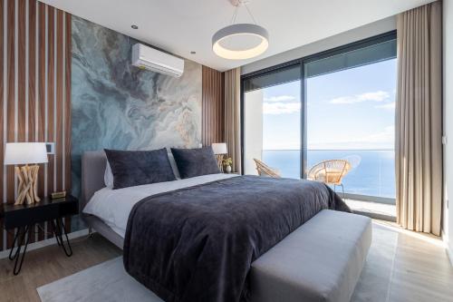 a bedroom with a large bed and a large window at The Cliffhouse by LovelyStay in Fajã da Ovelha