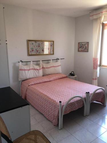 a bedroom with a bed with a pink bedspread at Appartamento vicino al mare e al centro in Alghero