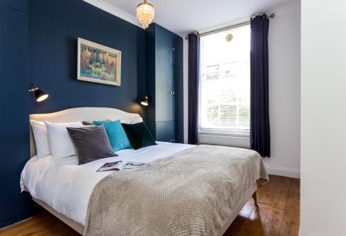 ロンドンにあるDear Newton One Bedroom in Notting Hillの青い壁のベッドルーム1室(大型ベッド1台付)