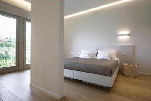 a white bedroom with a bed and a large window at Dame di Toscana in Lastra a Signa