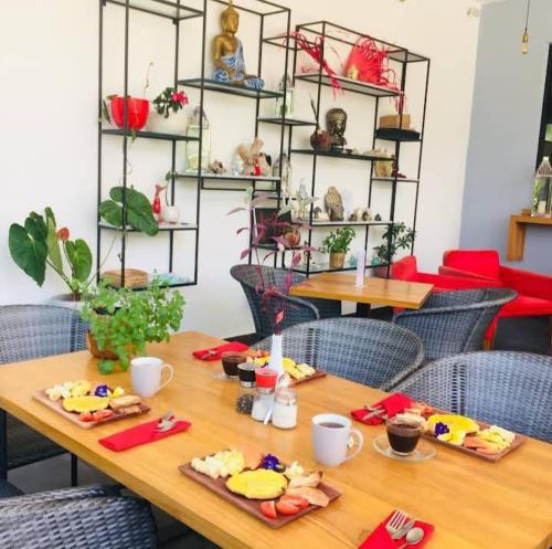 a wooden table with plates of food on it at Le Chien Rouge in Lovina