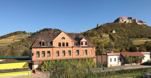 an old building on top of a hill with a castle at Pension Unstrutpromenade in Freyburg