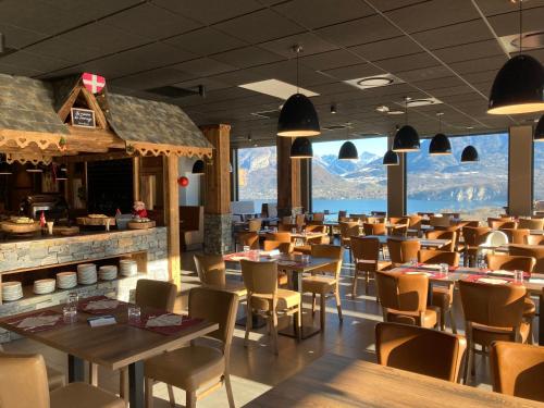 un restaurante con mesas y sillas y montañas de fondo en Village Club Les Balcons du Lac d'Annecy - Neaclub, en Sévrier