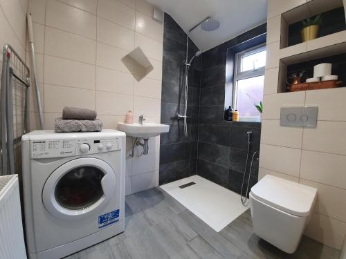 y baño con lavadora y lavamanos. en Victorian Home, 3BR, Airport, M1, 6 beds, sleeps 12, en Luton