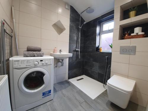 a bathroom with a washing machine and a sink at Wimborne House, 3BR, Airport, M1, 6 beds in Luton