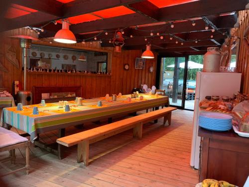 une salle à manger avec une longue table avec des bancs dans l'établissement Au Bois Flotté, à Hourtin