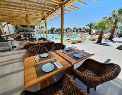 restauracja ze stołem i krzesłami przy basenie w obiekcie Smy Mediterranean White Santorini w mieście Kamari