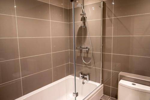 a bathroom with a shower with a tub and a toilet at The Helaina Apartments in Scarborough