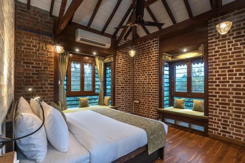 a bedroom with a white bed in a brick wall at SaffronStays Vedika - EcoFriendly villa by the River with Pool in Pālghar