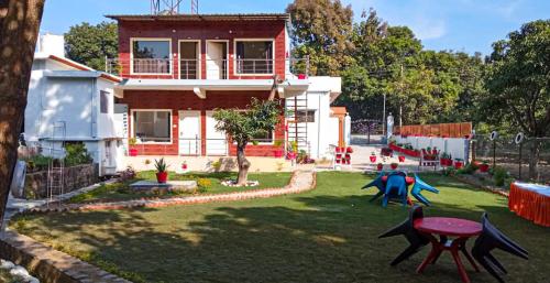 a house with a yard with playground equipment in front of it at Anugraha Homestay in Rāmnagar