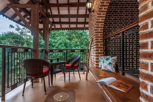 a room with a table and chairs on a balcony at SaffronStays Vedika - EcoFriendly villa by the River with Pool in Pālghar