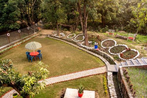 a garden with a table and chairs and an umbrella at Anugraha Homestay in Rāmnagar