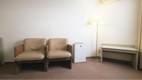 2 Stühle in einem Zimmer mit einer Lampe und einem Tisch in der Unterkunft Hotel New Century in Okinawa