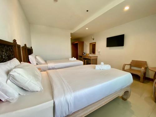 a hotel room with two beds and a television at At Ruam Chok Hotel in Chiang Mai