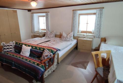 a bedroom with two beds and a chair and two windows at Fembacherhof in Siegsdorf