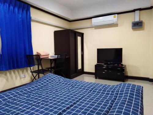 a bedroom with a blue bed and a tv at SRS3 STUDIO APARTMENT in Ban Bang Kha