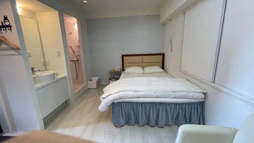 a bedroom with a bed and a sink and a bathroom at HotelHarmony日暮里ホテルハーモニー in Tokyo