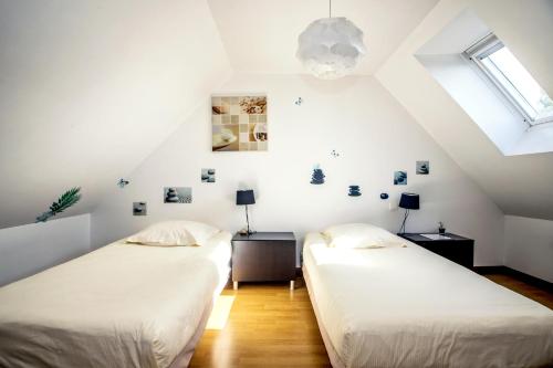 two beds in a attic room with white walls at Theven Plages in Santec