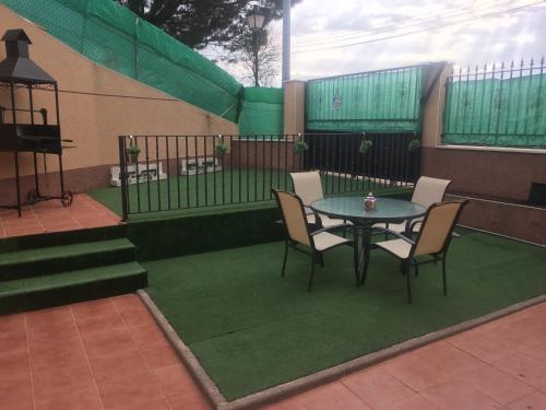 un patio con mesa, sillas y una valla en Casa Rural cueva cerros en Fuentidueña de Tajo