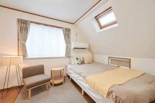 a bedroom with a bed and a chair and a window at 上落合ハウス KAMIOCHIAI HOUSE in Tokyo