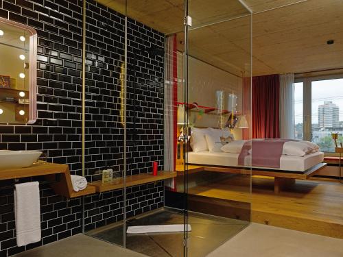 a bathroom with a bed and a glass shower at 25hours Hotel Langstrasse in Zürich