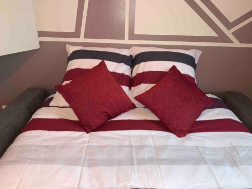 - un lit avec des oreillers rouges et blancs dans l'établissement Le Petit Toulouse, à Niort