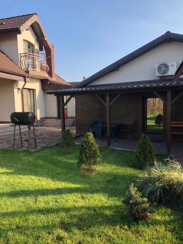 une maison avec une terrasse et un barbecue dans la cour dans l'établissement Casa Adrian, à Hîrşova