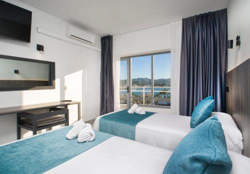 ein Hotelzimmer mit zwei Betten und einem Fernseher in der Unterkunft Hotel Base - Adults Only in Sant Antoni de Portmany