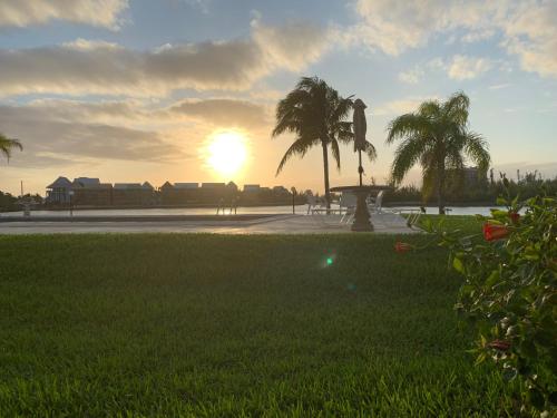 a sunset in a park with palm trees and grass at Obera Beach #105 in Freeport
