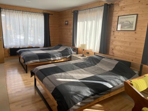two beds in a room with wooden walls and windows at Alexandar studio apartman in Mokra Gora