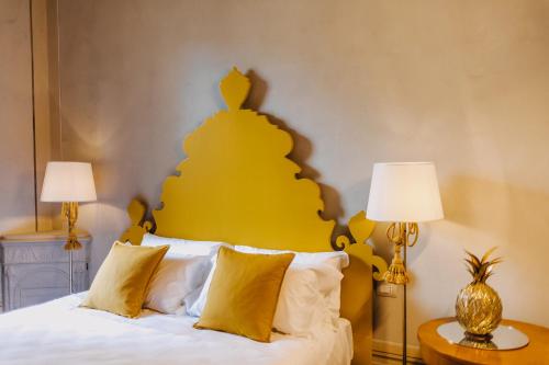 a bedroom with a white bed with a yellow headboard at Palazzo Feroci - Residenza d'epoca in Pisa